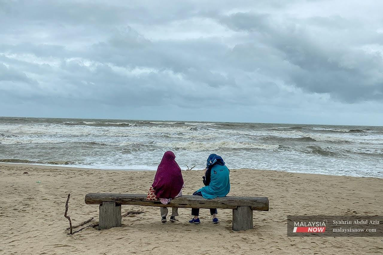 Dua orang pengunjung duduk berehat sambil melihat ombak di Pantai Batu Buruk, Kuala Terengganu.