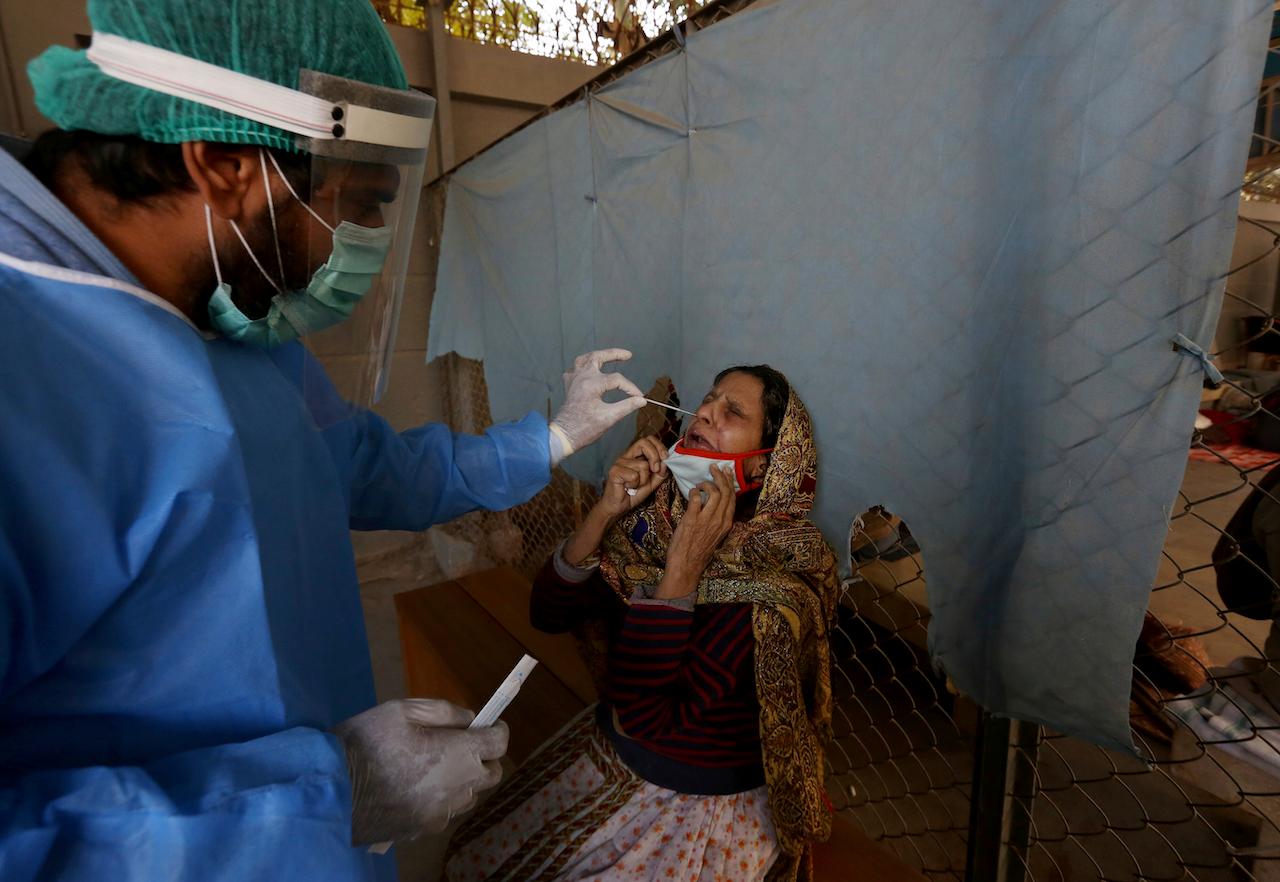 A healthcare worker takes a nasal swab sample from a woman at a Covid-19 testing facility at a hospital in Karachi, Pakistan, Dec 30, 2020. Photo: AP