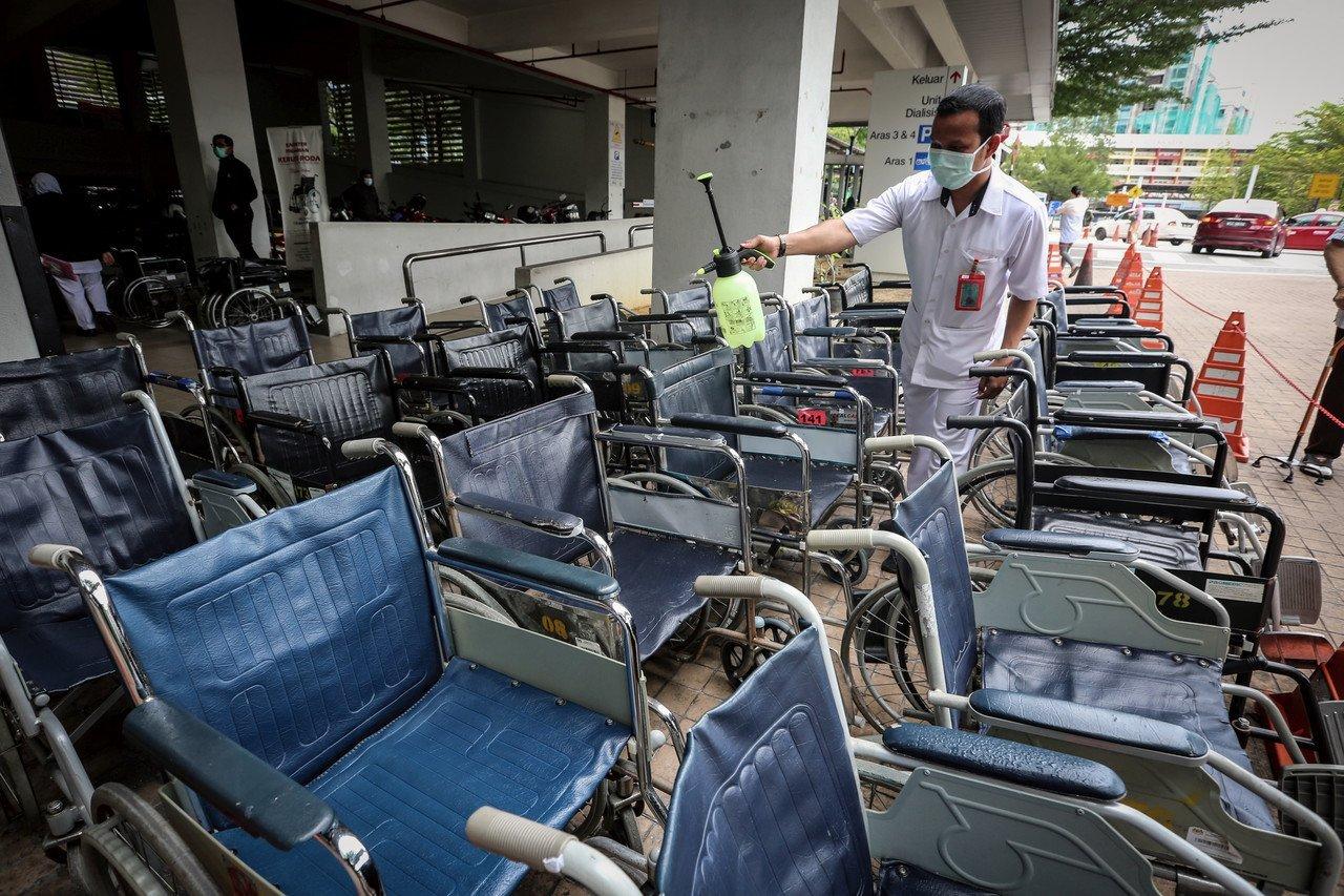 Pembantu Perawatan Kesihatan (PPK) Hospital Kuala Lumpur (HKL) melakukan semburan nyahkuman pada setiap kerusi roda selepas digunakan oleh pesakit yang mendapatkan rawatan di hospital berkenaan bagi mengekang penularan Covid-19. Gambar: Bernama