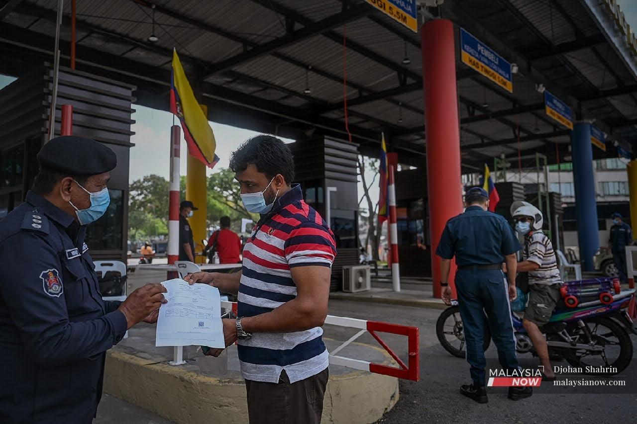 Penguat kuasa Dewan Bandaraya Kuala Lumpur memeriksa dokumen sebelum membenar penghantar barangan masuk ke kawasan Pasar Borong Kuala Lumpur.