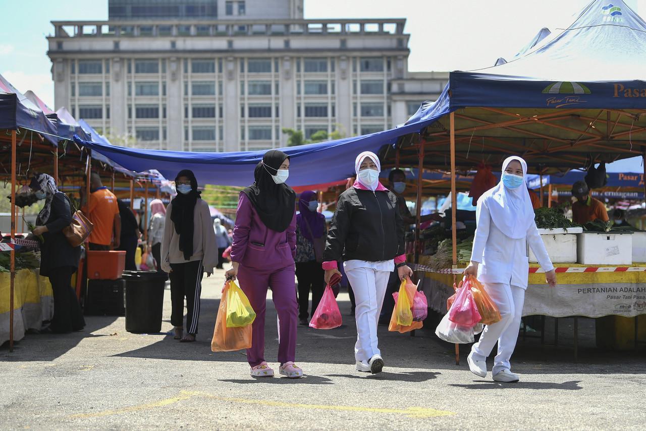 Petugas barisan hadapan membeli barang keperluan harian semasa waktu rehat tengahari di Pasar Tani Putrajaya dengan mematuhi Prosedur Operasi Standard (SOP) yang ditetapkan Majlis Keselamatan Negara (MKN) memakai pelitup muka serta mengamalkan penjarakan sosial pada 26 Januari, 2021. Gambar: Bernama