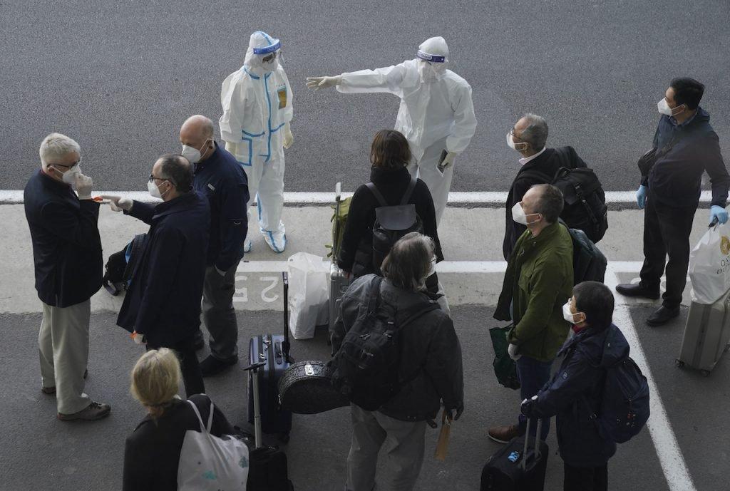 A worker in protective equipment directs members of the World Health Organization team on their arrival at the airport in Wuhan in central China's Hubei province, Jan 14. Photo: AP