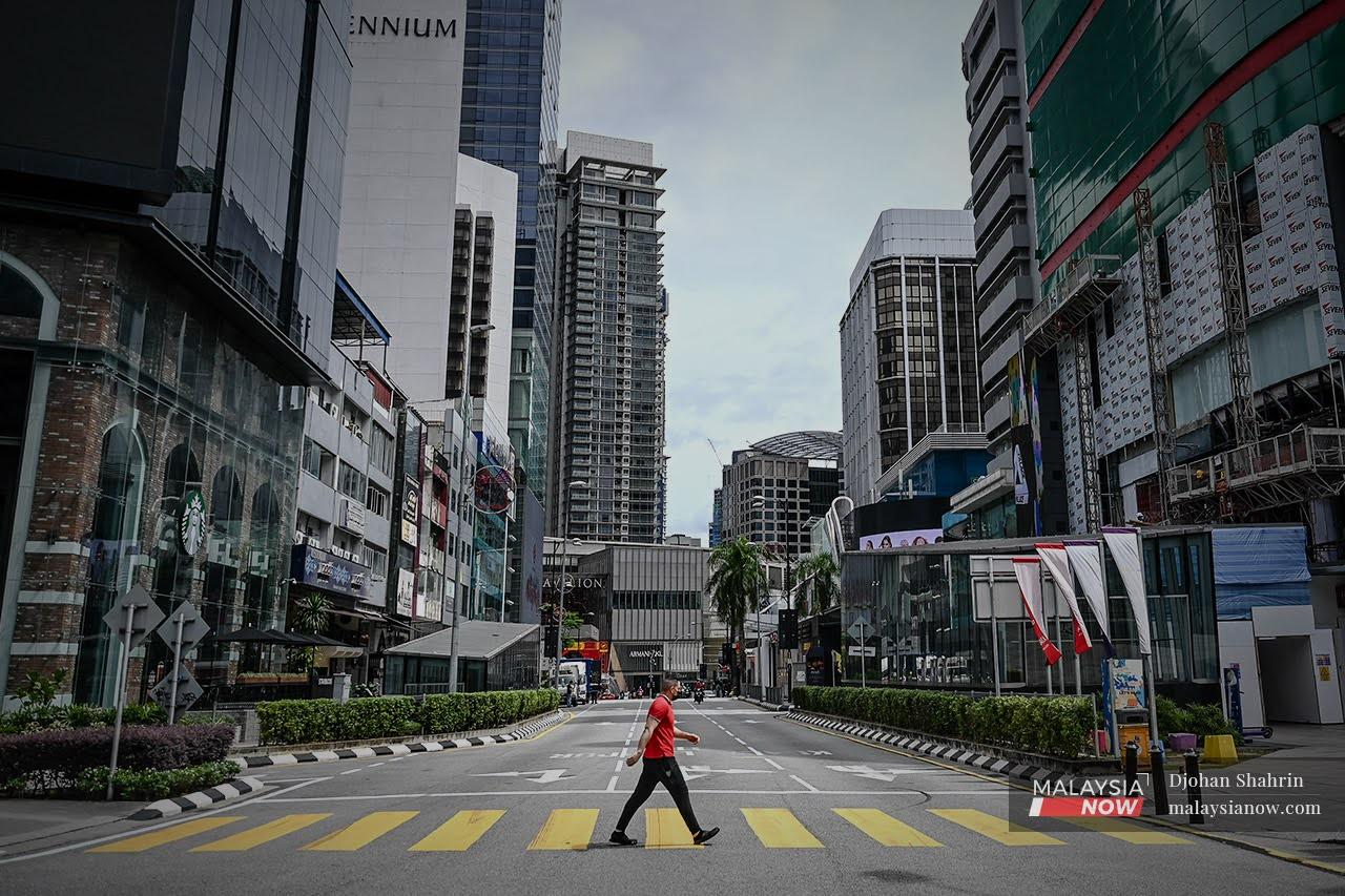Shops and streets lie quiet as a pedestrian crosses a road in downtown Kuala Lumpur on Jan 14, a day after the movement control order came into effect across large parts of the country. Authorities are trying to strike a balance between lives and livelihoods as the Feb 4 deadline for the movement restrictions approaches.