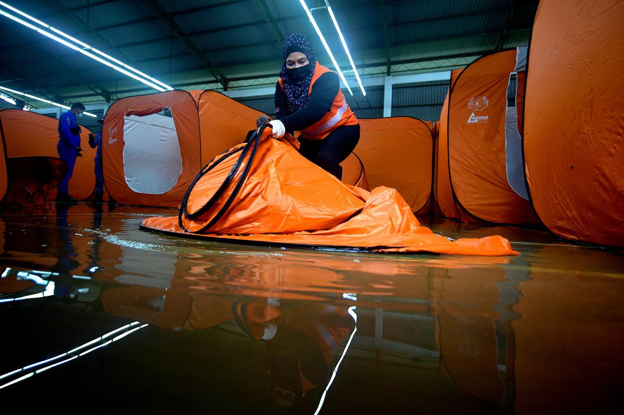 Sukarelawan Jabatan Kebajikan Masyarakat Sarawak melipat semula khemah di Pusat Pemindahan Sementara (PPS) di Dewan Taman Malihah setelah pusat itu dinaiki air pada 14 Januari, 2021. Gambar: Bernama