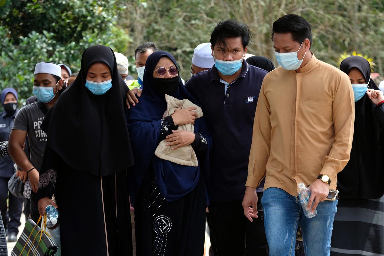 Ibu angkat kepada kanak-kanak lelaki berusia tujuh tahun yang maut, Norlida Abu Hassan, 50, (depan, tiga kanan) memeluk erat bantal busuk milik kanak-kanak itu ketika hadir pada majlis pengkebumian di Tanah Perkuburan Islam Padang Lebar dekat Simpang Bekoh di Jasin hari ini. Gambar: Bernama