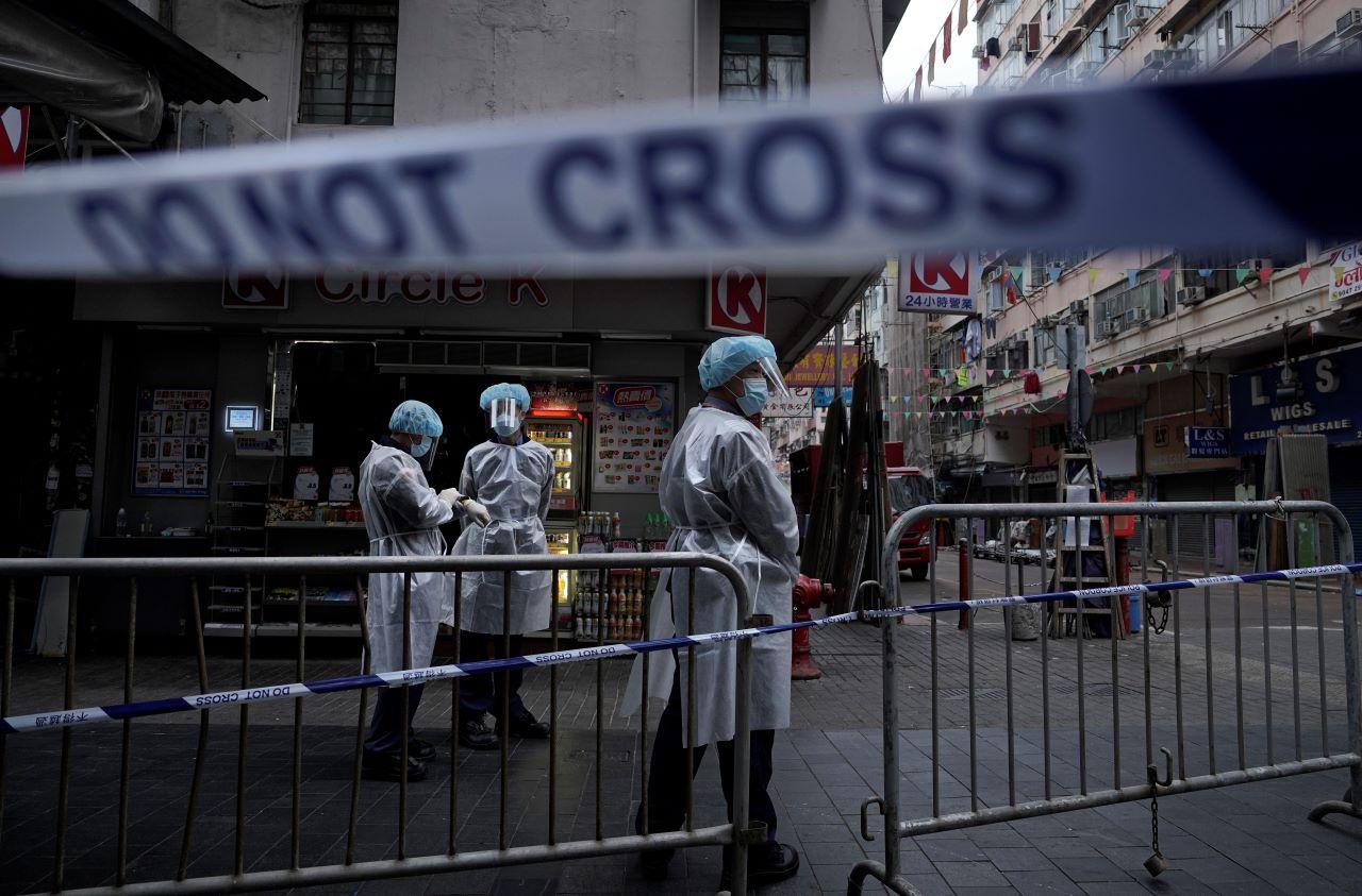 Government workers wearing personal protective equipment stand guard at a closed-off area in Jordan district, in Hong Kong, Jan 24. Thousands of Hong Kong residents were locked down in an unprecedented move to contain a worsening outbreak in the city, authorities said. Photo: AP