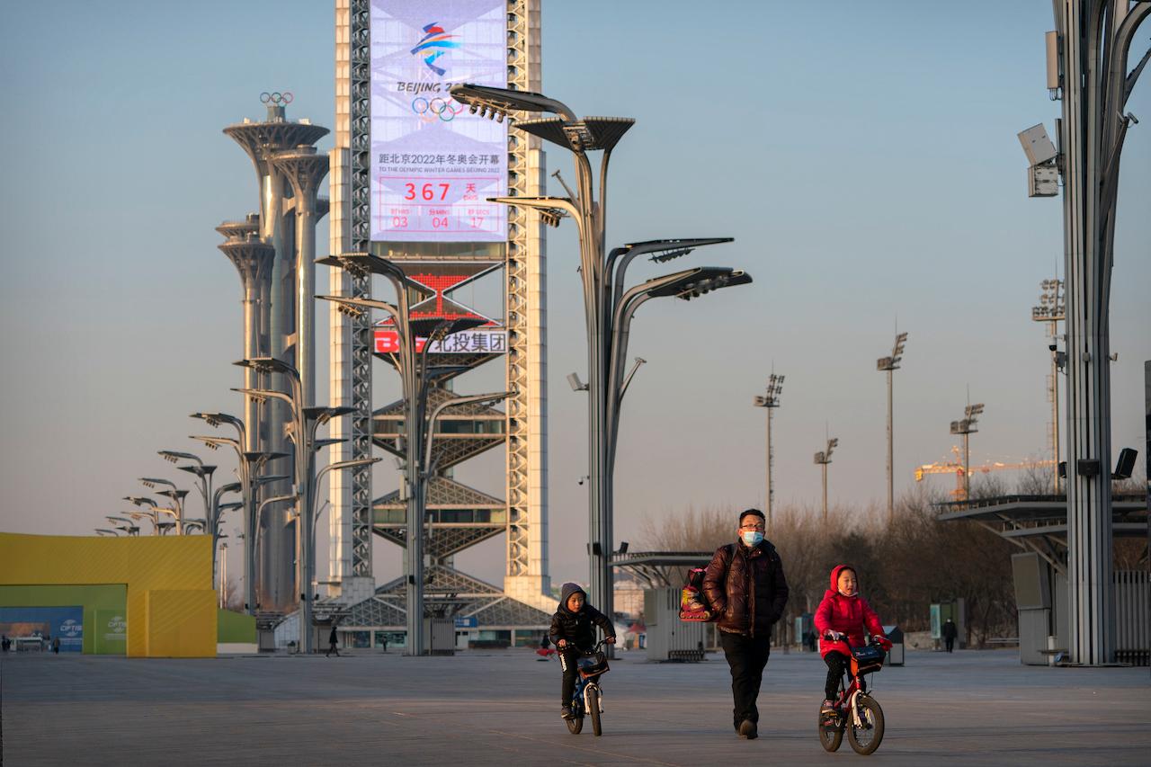 People walk on the Olympic Green near a countdown clock showing slightly more than a year to go for the 2022 Beijing Olympics in Beijing, Feb 2. Photo: AP