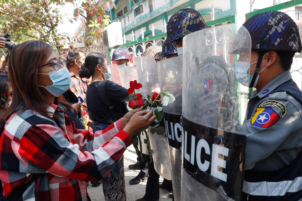 Supporters give roses to police while four arrested activists make a court appearance in Mandalay, Myanmar, Feb 5. Hundreds of students and teachers have taken to Myanmar's streets to demand the military hand power back to elected politicians, as resistance to a coup swelled with demonstrations in several parts of the country. Photo: AP