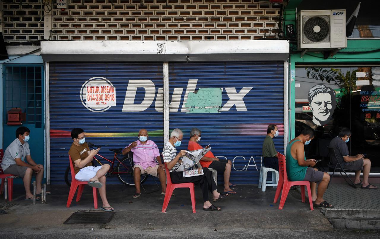 Customers wait for their turn outside a barbershop in Kuantan following the green light from the government for barbers to resume business during the movement control order period. Photo: Bernama
