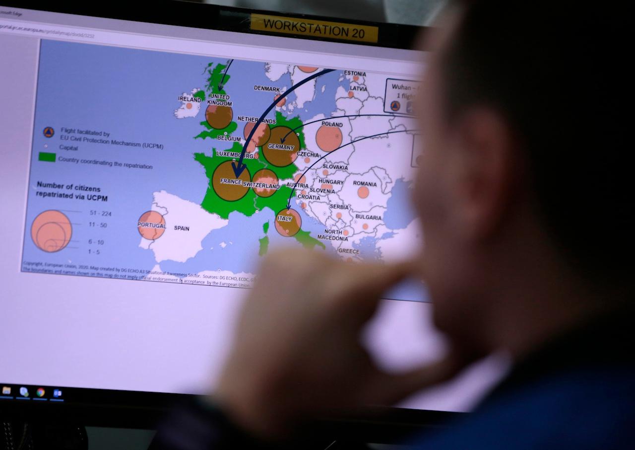An exmployee at the Emergency Response Coordination Center in Brussels views a screen with graphics regarding the spread of Covid-19. More than 119 million doses of vaccine have been distributed worldwide. Photo: AP
