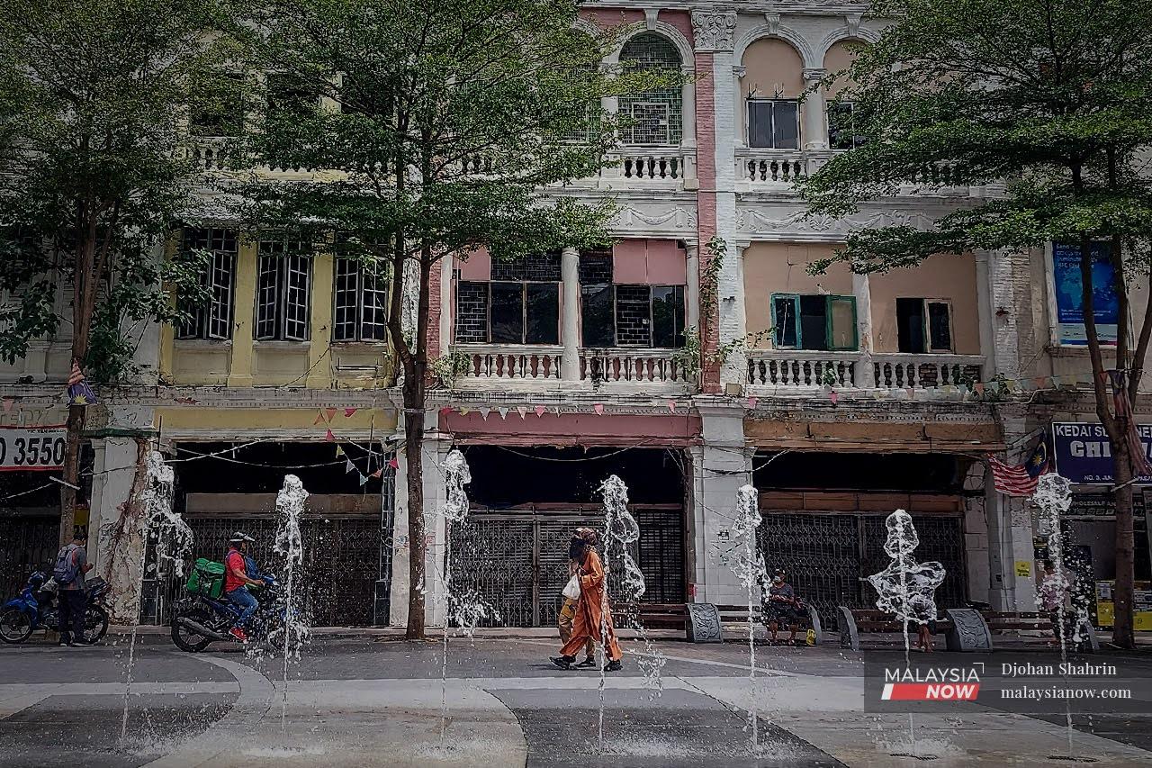 Pedestrians walk past a row of old shophouses at Medan Pasar in Lebuh Ampang, Kuala Lumpur.