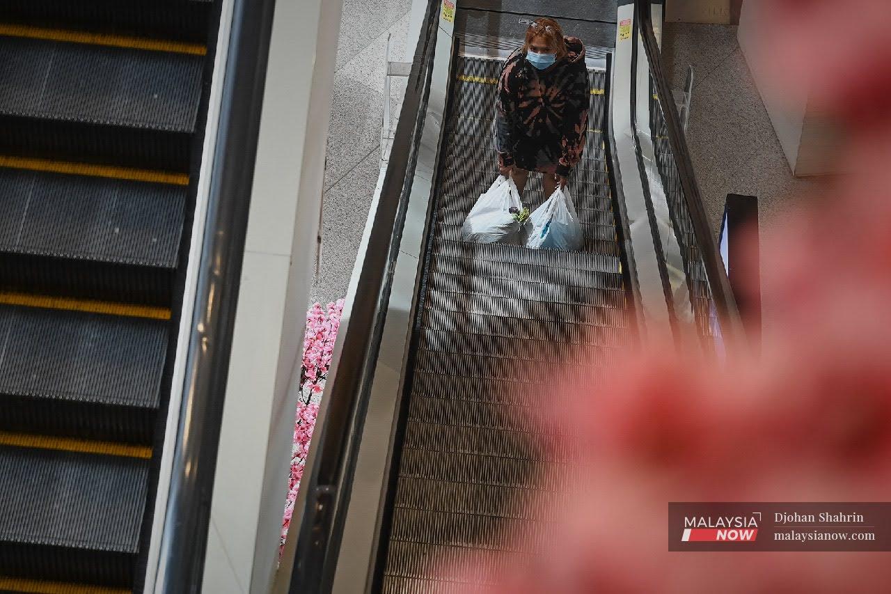 A woman rests her bags of groceries on the escalator at a mall in Kuala Lumpur.