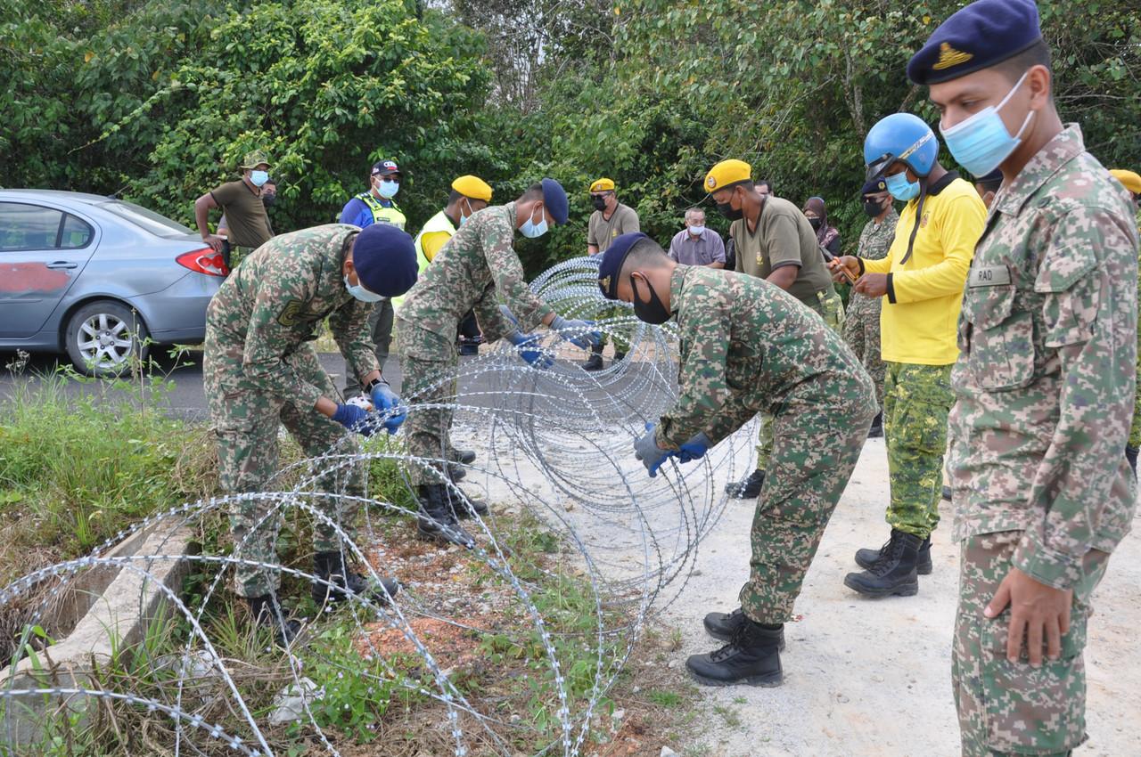 Anggota tentera yang dibantu Jabatan Sukarelawan Malaysia (Rela) memasang gelungan kawat duri di salah satu laluan tikus di sekitar kawasan sawah padi di Kampung Padang Baloh, Hulu Besut, semalam. Gambar: Bernama
