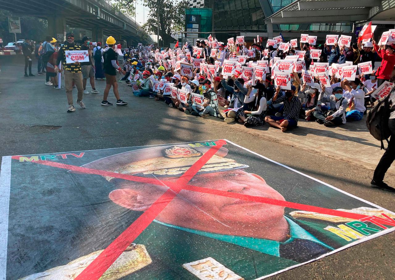 An image showing an X mark on the face of General Min Aung Hlaing lies on a road as anti-coup protesters gather outside the Hledan Centre in Yangon, Myanmar, Feb 14. Photo: AP