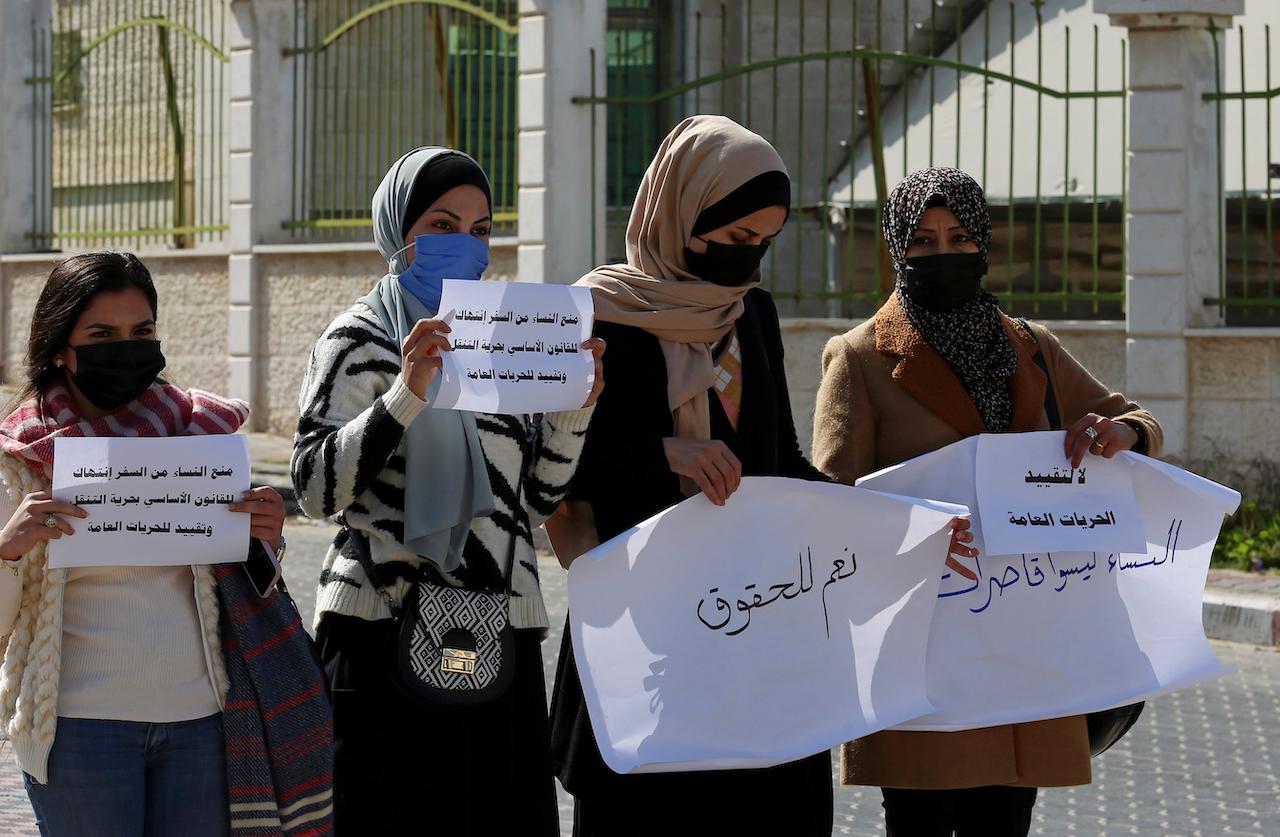 Women hold signs during a protest against the decision by the Sharia Judicial Council banning women from movement in and out of the Gaza Strip without the permission of a 'guardian', in front of the council, in Gaza City, Feb 16. Photo: AP