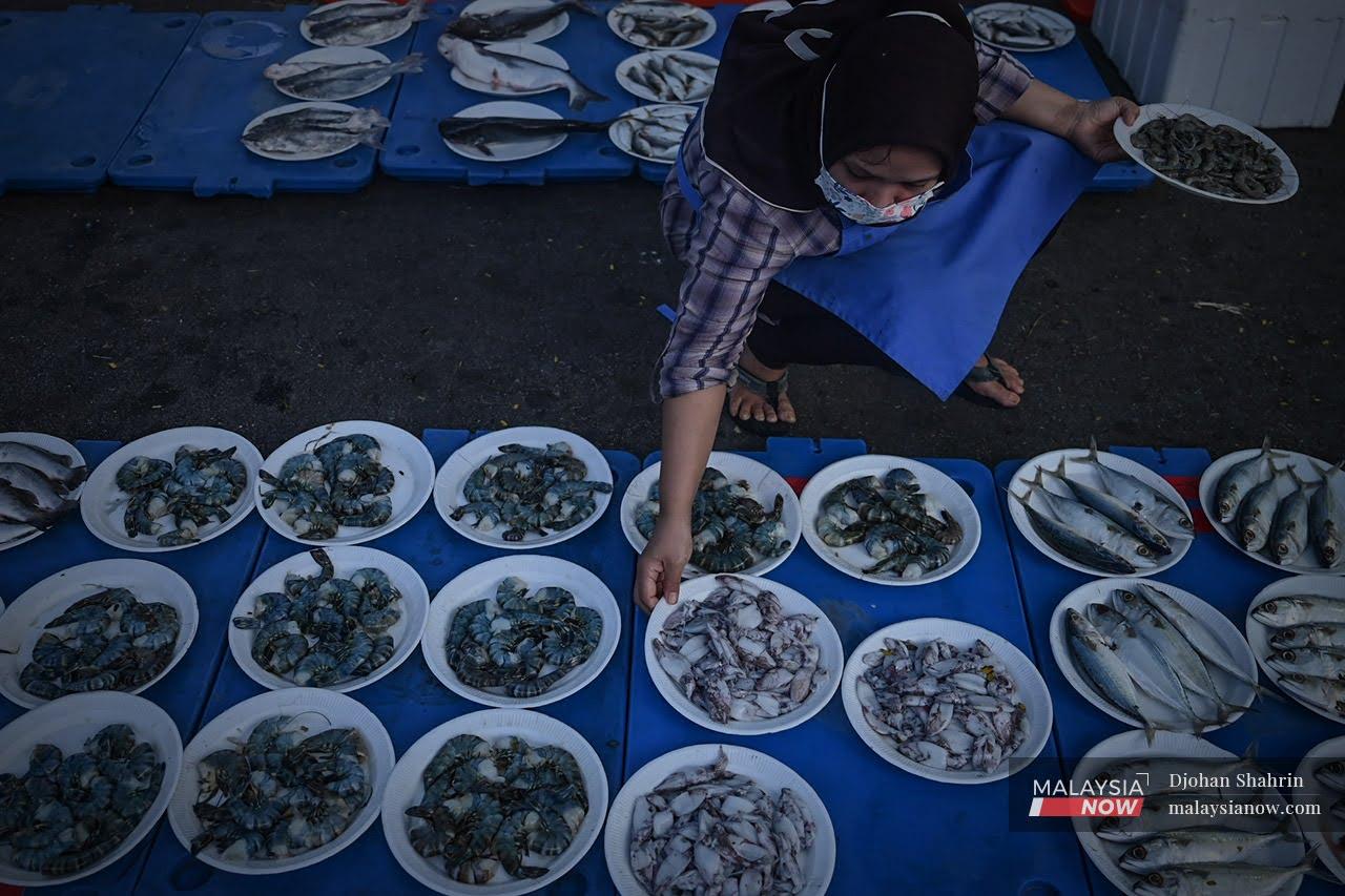 A resident of Desa Melawati chooses from plates of squid and prawns at Kiki Fish Market, a mobile market catering to the low-income group which has stopped for the day in Hulu Klang.