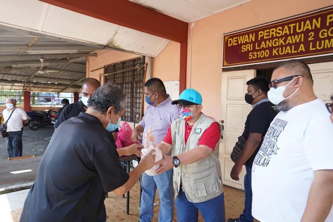 Ketua Penerangan PKR, Shamsul Iskandar Akin menyerahkan sumbangan ayam kepada seorang penduduk di Wangsa Maju, sambil diperhati pelakon Afdlin Shauki (kanan). Gambar: Facebook