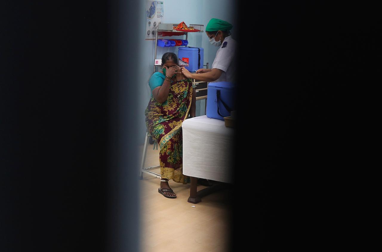 A health worker administering Covid-19 vaccine to a hospital staff is seen through a door in Mumbai, India, Feb 22. Photo: AP