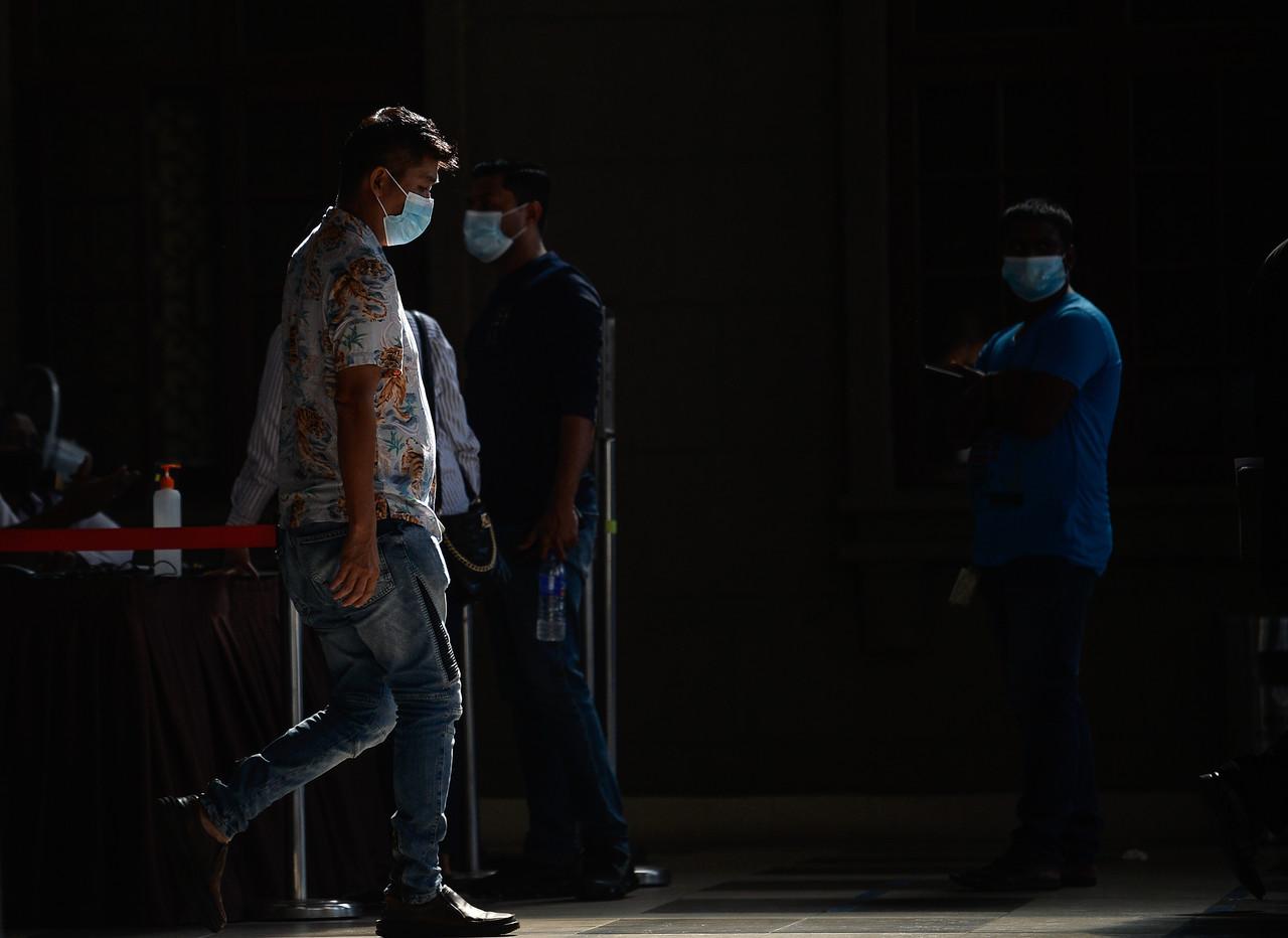People wearing face masks follow health SOPs including temperature checks and use of hand sanitiser in downtown Kuala Lumpur today. Photo: Bernama
