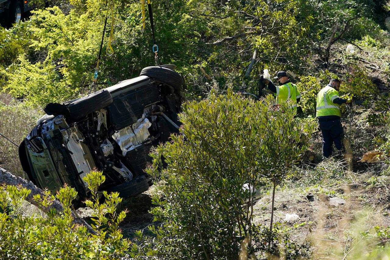 Workers collect debris beside a vehicle after a rollover accident involving golfer Tiger Woods, Feb 23, in Rancho Palos Verdes, California. Woods suffered leg injuries in the one-car accident and was undergoing surgery, authorities and his manager said. Photo: AP