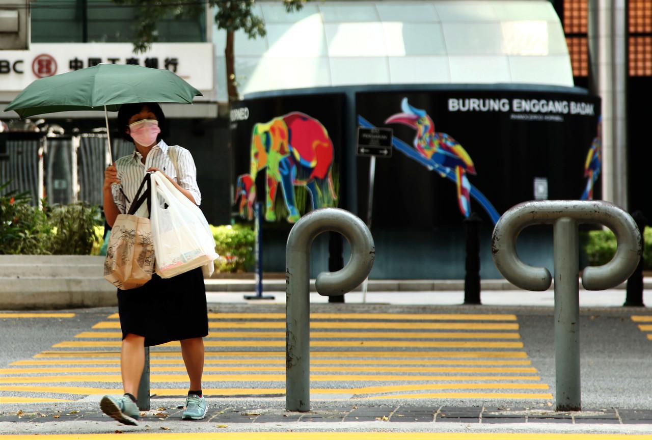 A woman wearing a face mask to prevent the spread of Covid-19 crosses a road in Kuala Lumpur. Photo: Bernama