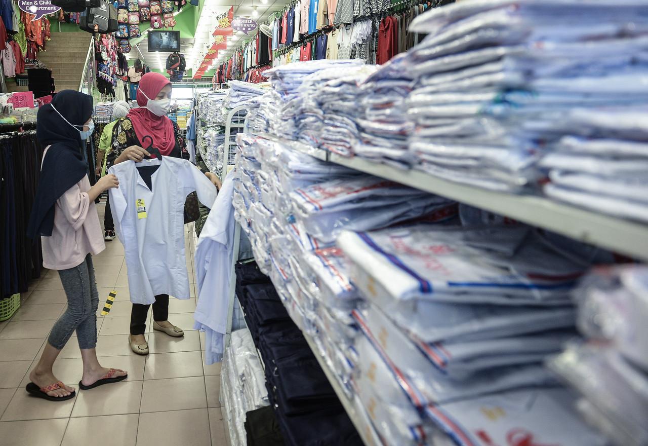 A parent shops for school uniforms for her daughter ahead of the reopening of schools beginning next week. Photo: Bernama