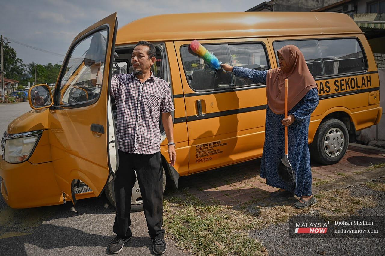 Ismail Raja Mat and his wife Norhayati Muda smile as they clean their school van ahead of school reopening next week. The van has stood empty throughout the movement control order but they hope it will soon be full again.
