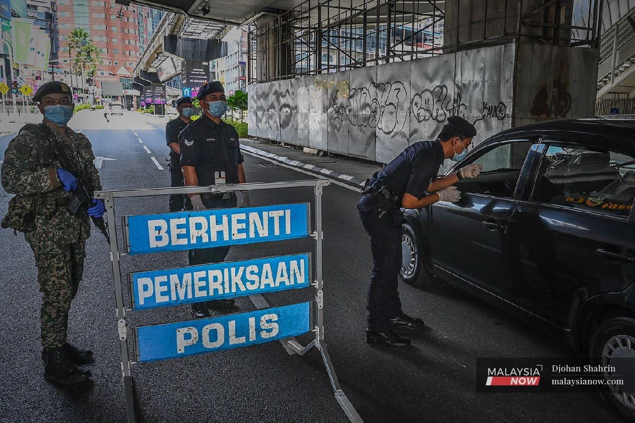 Police conduct checks at a roadblock in Kuala Lumpur during the movement control order period.
