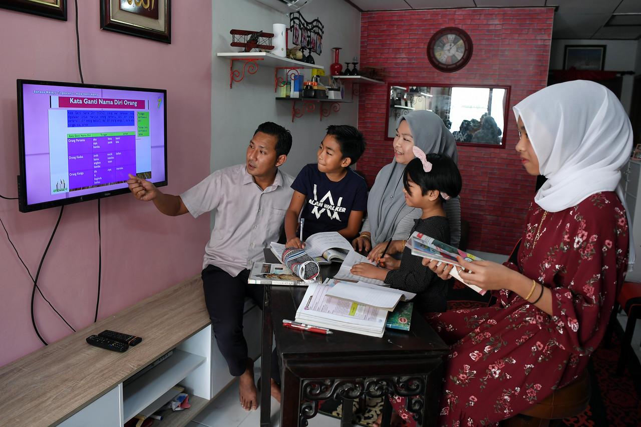 Zulkifli Mohamad, 38, (kiri) dan isteri, Nor Hidayu Zakaria, 39, (tiga, kiri) memantau sesi pembelajan anak-anak mereka menerusi saluran program DidikTV di Taman Adis Indah, Kuala Ibai baru-baru ini. Gambar: Bernama