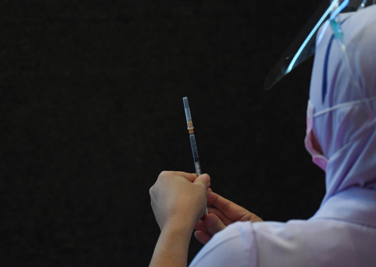 A health worker prepares a syringe filled with the Pfizer-BioNTech vaccine to be administered to a frontliner in Kuantan, Pahang. Photo: Bernama