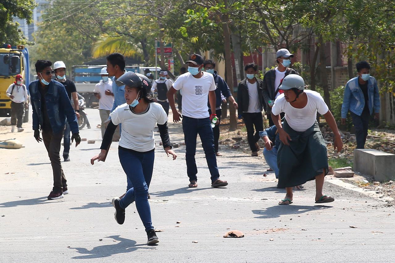 Protesters run as police fire tear gas during a protest against the military coup in Mandalay, Myanmar, Feb 28. Security forces in Myanmar used lethal force as they intensified their efforts to break up protests a month after the military staged a coup. Photo: AP