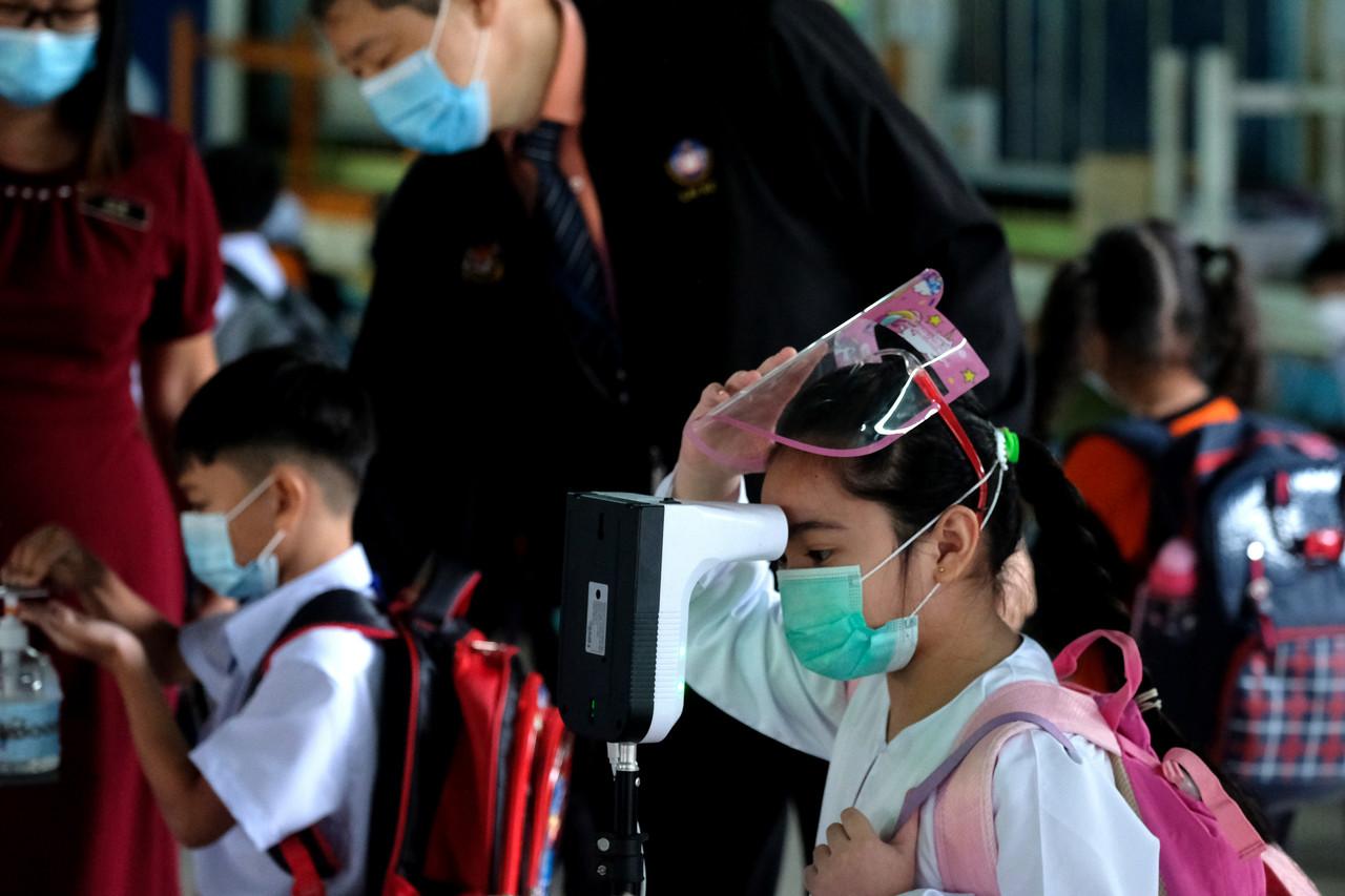 A Standard 1 pupil at SK St Monica in Sandakan, Sabah, checks her temperature before entering the school compound to begin the first day of face-to-face classes this year. Photo: Bernama