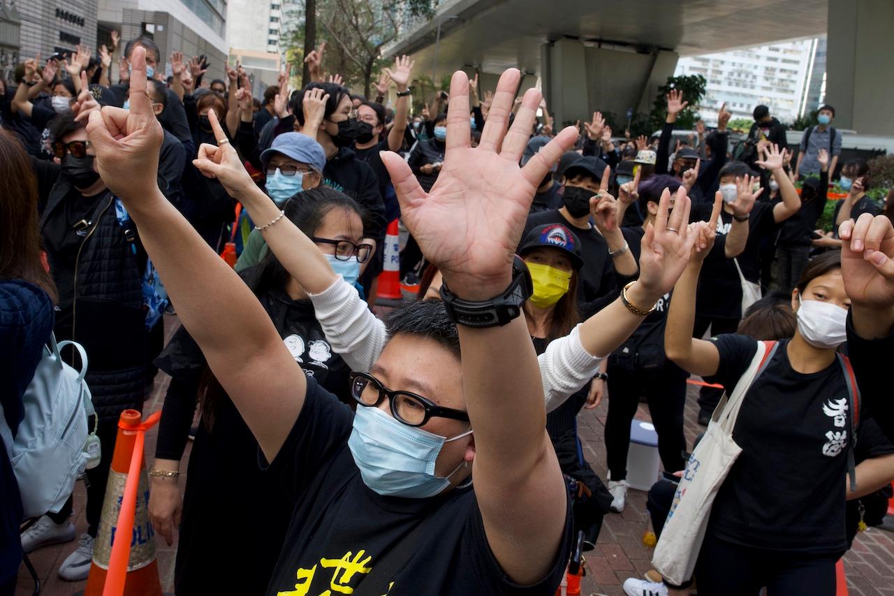 Supporters gesture with five fingers, signifying 'Five demands – not one less' outside a court in Hong Kong, March 1. Police brought 47 pro-democracy activists to court on charges of conspiracy to commit subversion under the national security law imposed on the city by Beijing last year. Photo: AP