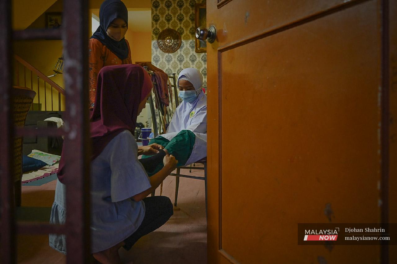 A mother helps her daughter pull on her socks at their home in Ampang, Kuala Lumpur, on the first day back at school for pupils in Standard 1 and 2.