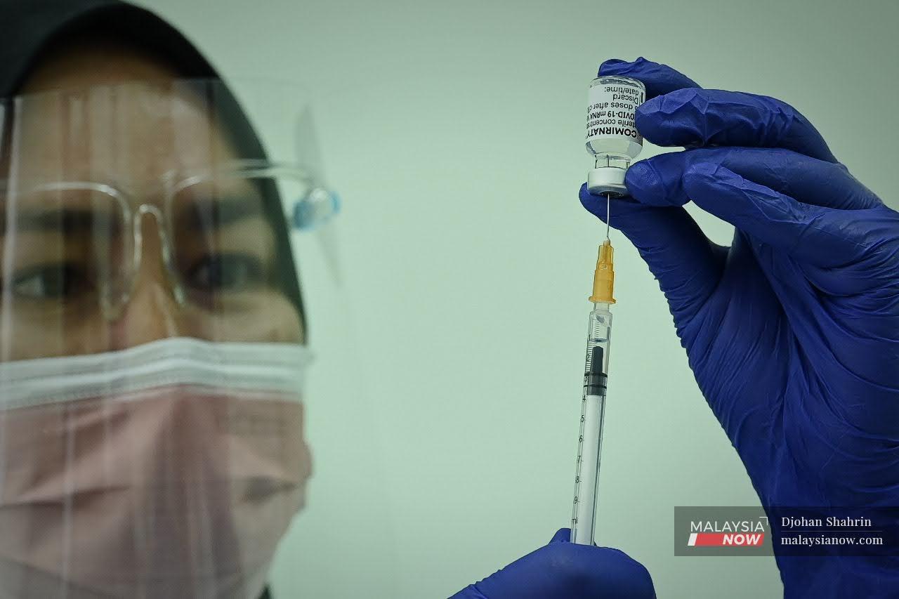 A medical assistant at Hospital UiTM in Sungai Buloh prepares a syringe of Pfizer-BioNTech vaccine for administration today. Under the guidelines for the national vaccination programme, private healthcare workers are listed under Category 2 along with other essential services personnel.