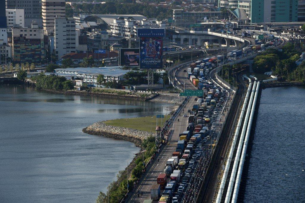 Vehicles queue to enter the Woodlands checkpoint in Singapore from the Johor causeway. A Singaporean who managed to buy a gun in Malaysia and smuggle it into the city-state has been sentenced to nearly eight years jail with six strokes of the cane. Photo: AFP