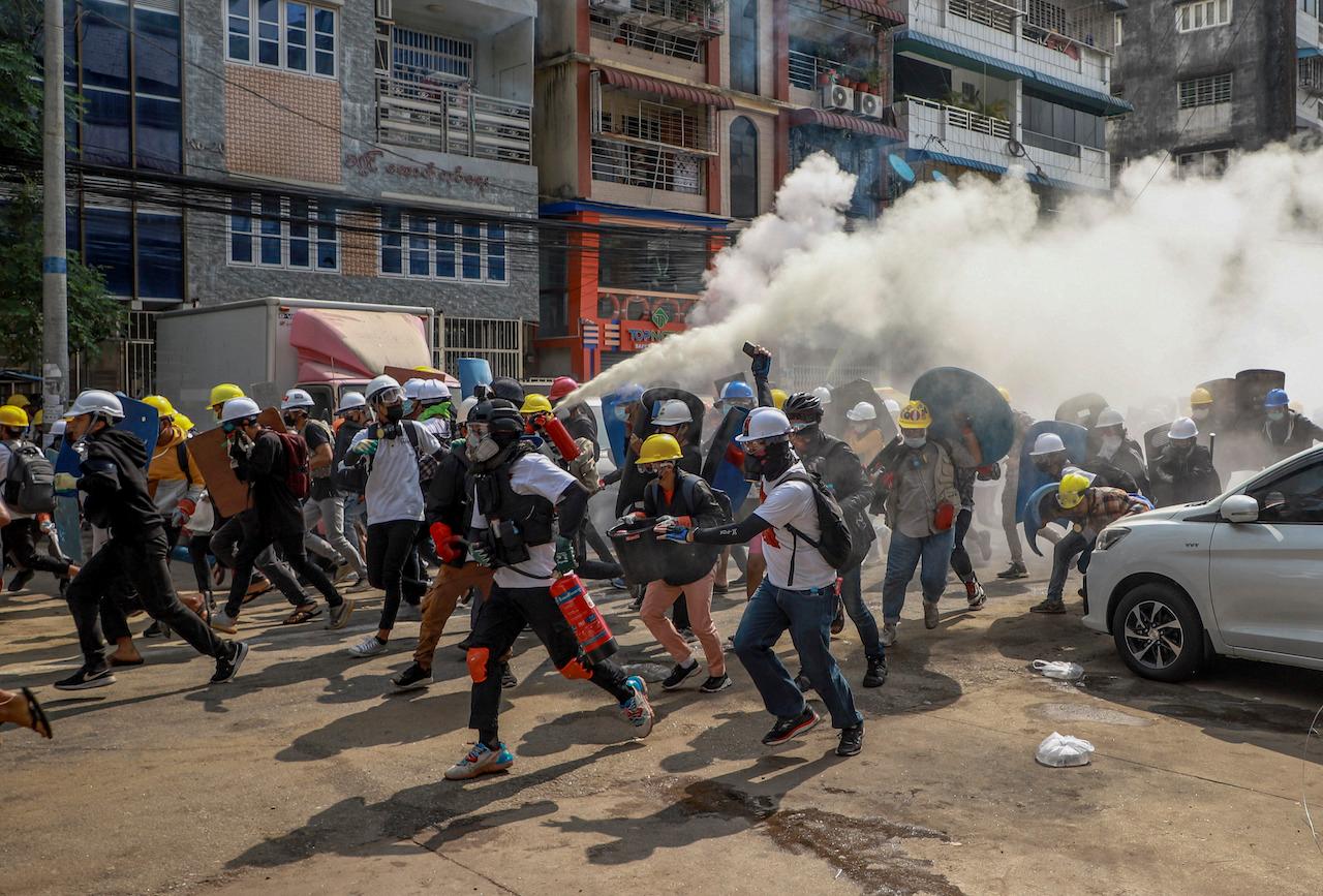 Anti-coup protesters run, one of them discharging a fire extinguisher to counter the impact of tear gas fired by riot policemen in Yangon, Myanmar, March 3. Demonstrators in Myanmar took to the streets again to protest last month's seizure of power by the military. Photo: AP