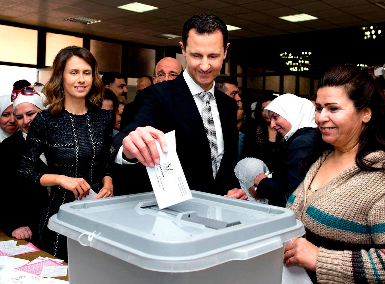 This April 13, 2016 file photo shows Syrian President Bashar Assad casting his ballot in the parliamentary elections, as his wife Asma (left) stands next to him, in Damascus, Syria. Assad's office said Monday that he and his wife have tested positive for the coronavirus but are doing well. Photo: AP