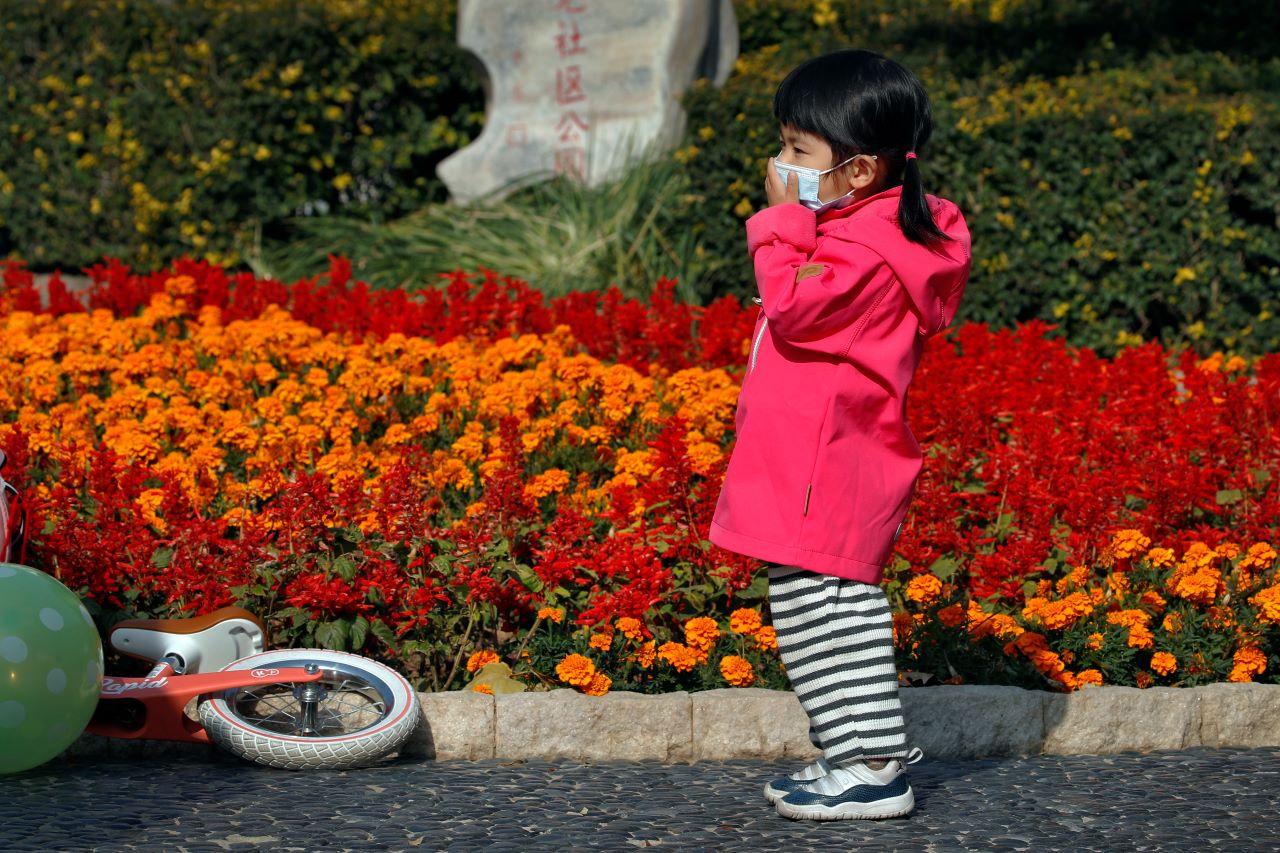 A child holds her face mask in place to help curb the spread of the Covid-19 while she plays at a park in Beijing, Nov 5, 2020. China has launched a health certificate showing a user's vaccination status and virus test results to pave the way for a resumption of travel. Photo: AP