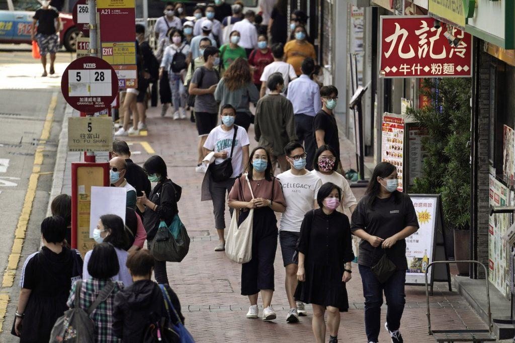 People wearing masks to protect against the coronavirus walk down a street in Hong Kong on Oct 9. Hong Kong considers it unlikely that full cross-border travel will resume soon, although tourists may be welcomed from selected markets. Photo: AP