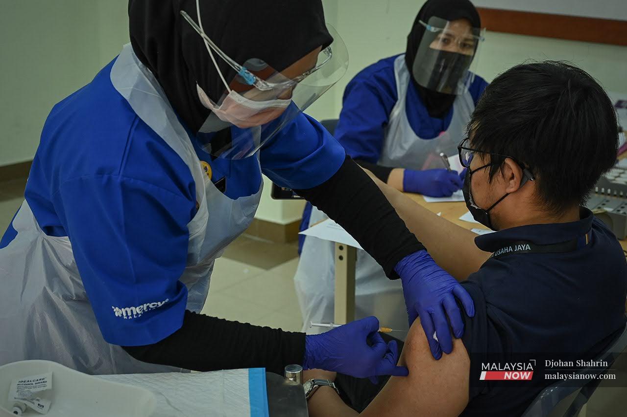 A frontliner receives his first dose of the Pfizer-BioNTech vaccine at Hospital UiTM in Sungai Buloh, Selangor.