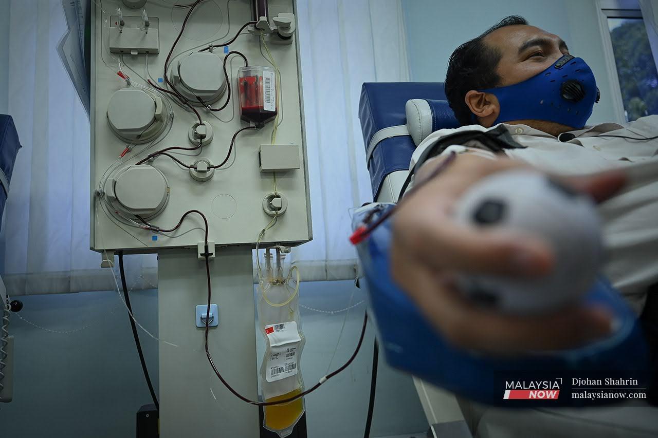 A man donating plasma at the National Blood Centre in Kuala Lumpur clenches his fist around a small ball to stimulate blood flow. The centre has been facing a shortage of blood supply since the Covid-19 pandemic hit.
