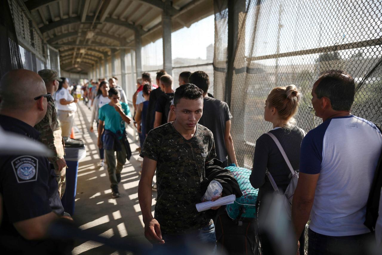 In this Aug 2, 2019 file photo, migrants return to Mexico as other migrants line up on their way to request asylum in the US, at the foot of the Puerta Mexico bridge in Matamoros, Mexico, that crosses into Brownsville, Texas. Photo: AP