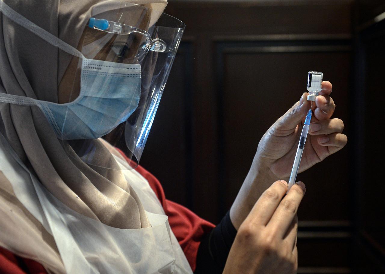 A healthcare worker prepares a syringe of Pfizer-BioNTech vaccine to be administered to frontliners at the Sunway Pyramid Convention Centre in Petaling Jaya. Photo: Bernama