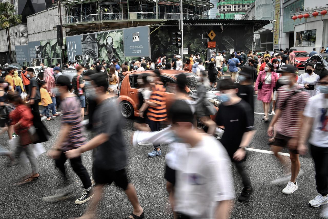 People wear face masks as a precaution against the spread of Covid-19 as they cross a road in Kuala Lumpur after it was put under conditional movement control order. Photo: Bernama