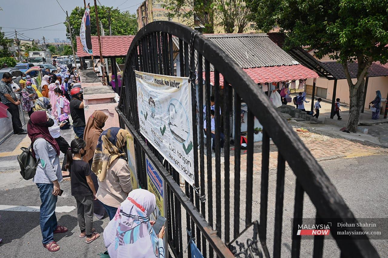 Parents gather outside the gate of a school in Ampang on March 1, when preschool and primary students were allowed to return to the classroom after months of home-based learning. Complaints have since emerged about some parents who do not observe SOPs such as physical distancing when picking up their children from school.