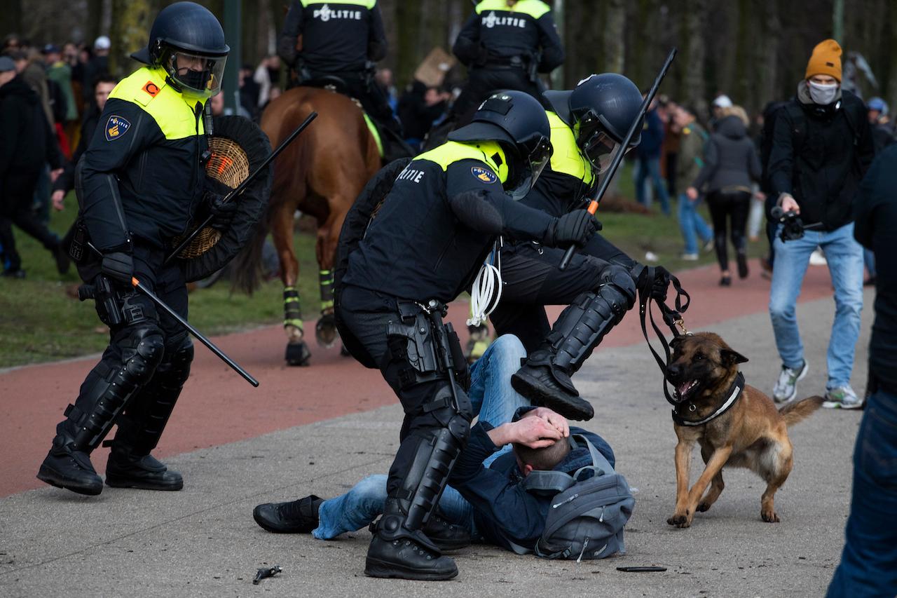 Dutch riot police kick a man during a demonstration to protest government policies including the curfew, lockdown and coronavirus-related restrictions in The Hague, Netherlands, March 14. Thousands of people took part in the rally ahead of three days of voting starting Monday in a general election. Photo: AP