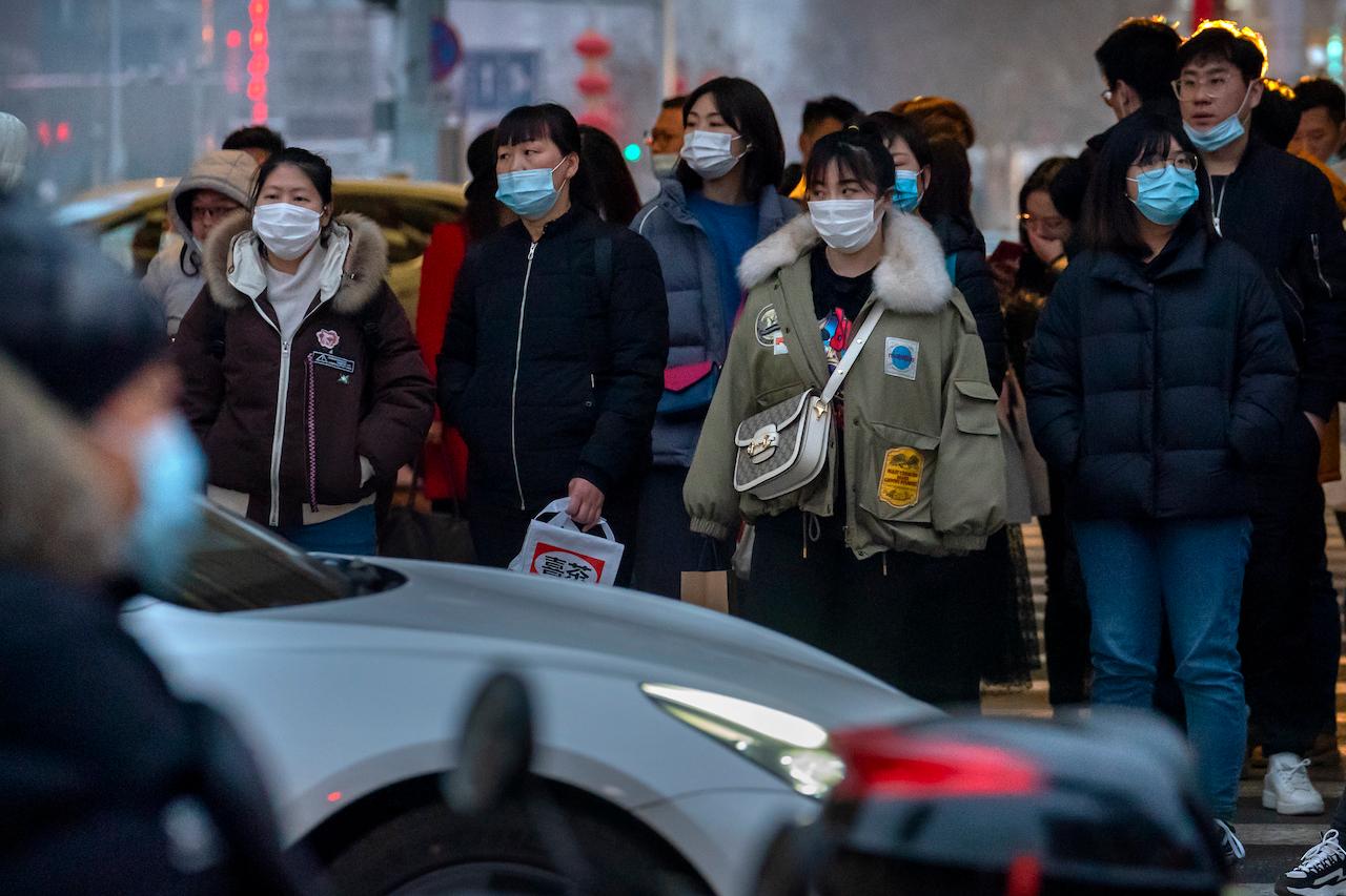 Commuters wearing face masks to protect against the spread of the coronavirus wait to cross an intersection in Beijing, March 3. Chinese companies are set to export nearly 400 million doses of home-grown vaccines overseas. Photo: AP