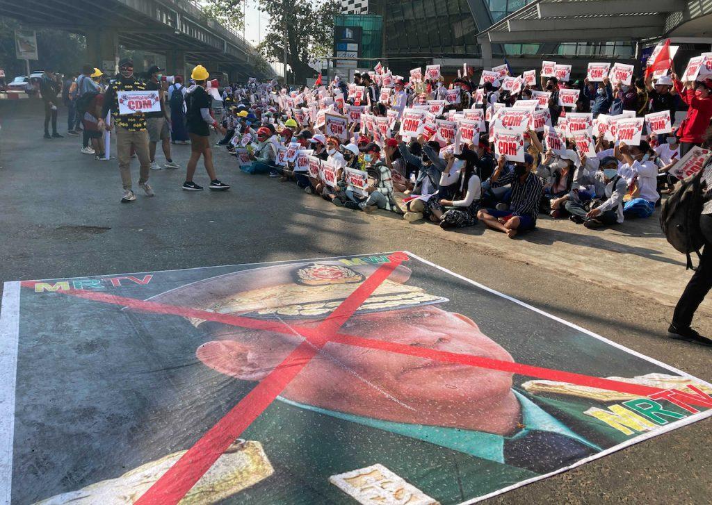 An image showing an X mark on the face of General Min Aung Hlaing lies on a road as anti-coup protesters gather outside the Hledan Centre in Yangon, Myanmar, Feb 14. Protesters have also launched an online campaign to denounce family members and associates of the junta living abroad. Photo: AP