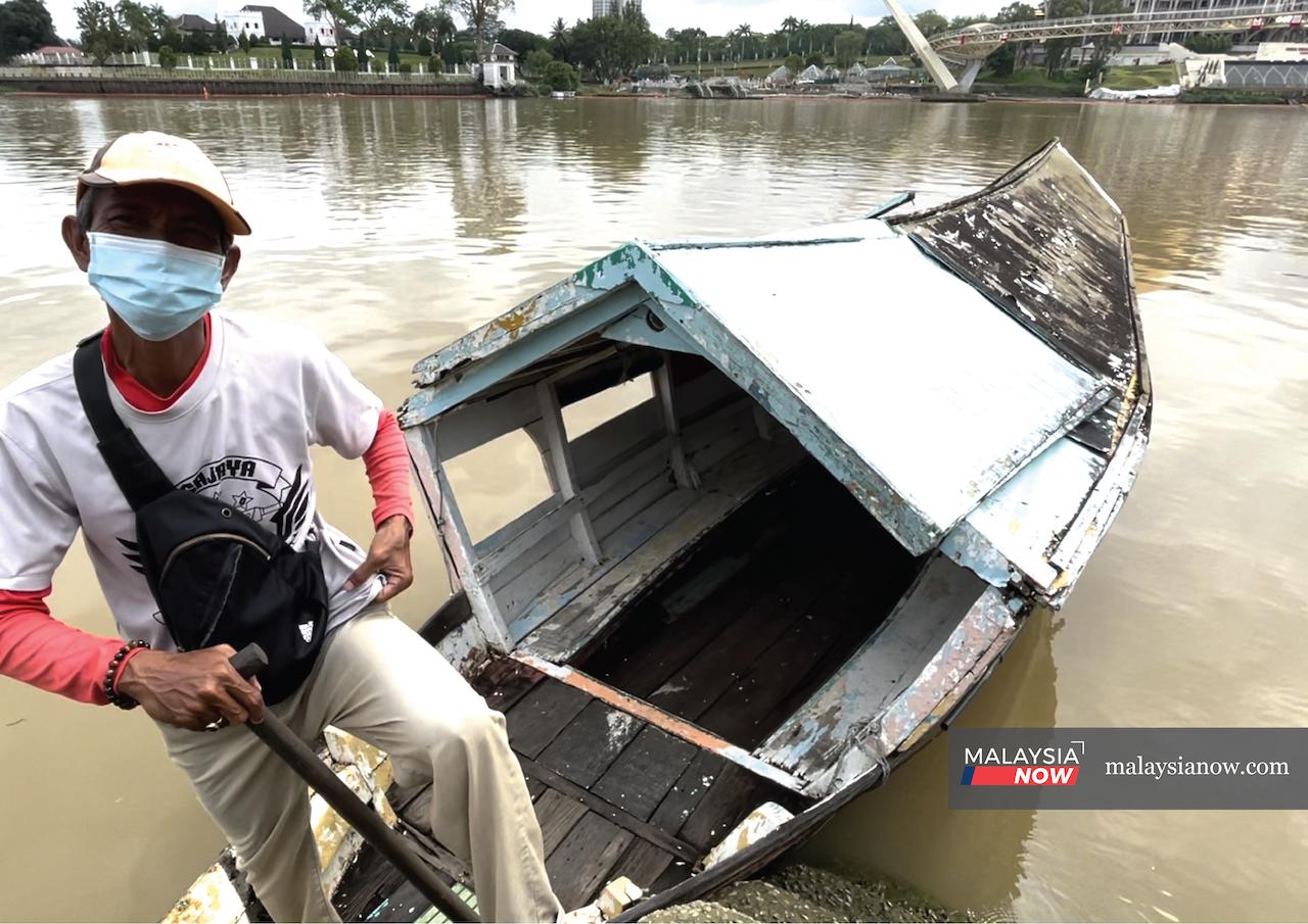 Ferryman Pak Openg with his 'river taxi': a small, covered wooden boat in which he ferries passengers to and fro along Sungai Sarawak.
